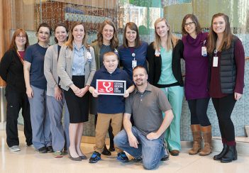 Members from the Pediatric Muscular Dystrophy Clinic gather around patient Xander and his dad, Coulter Little.