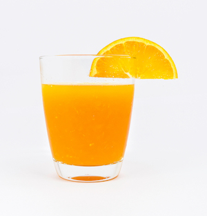 A glass of orange juice on a white background. An orange slice is mounted on the rim of the glass. It looks tasty, though the large orange slice might interfere with drinking.