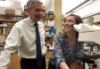Gary K. Owens, PhD, consults with researcher Molly R. Kelly-Goss at a microscope.