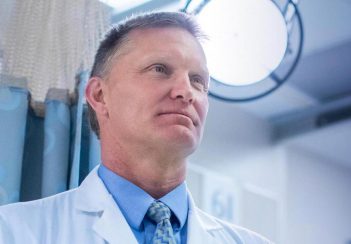 Dr. Chris Holstege looks off-camera in a clinical setting.