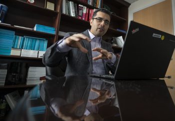 Hessam Sadatsafavi gestures while sitting behind an open laptop.