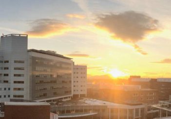 The sun sets in the distance behind the UVA Health hospital buildings.