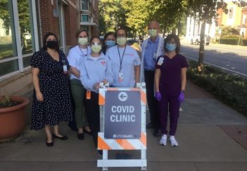 The COVID-19 reseach team stands outside UVA's COVID Clinic. They are masked.