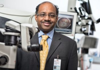 Jayakrisha Ambati smiles amid microscopes and other equipment in his lab.