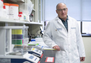 Dr. Steven Zeichner stands next to a lab bench.