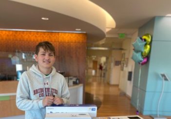 Luke Post stands behind gaming consoles and other activities donated to UVA Children's.