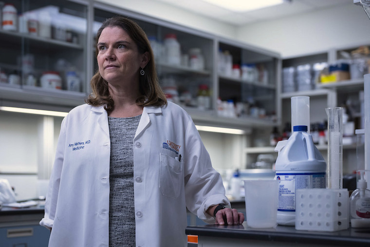 Dr. Amy Mathers wears a white coat in a lab.
