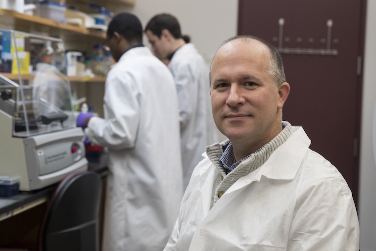 Jason Papin wears a white coat in his lab.