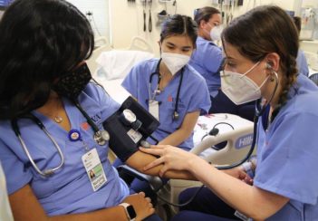 Nursing students practice taking blood pressure.