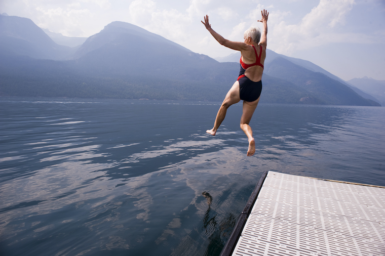 Babyboomer woman jumps in a lake